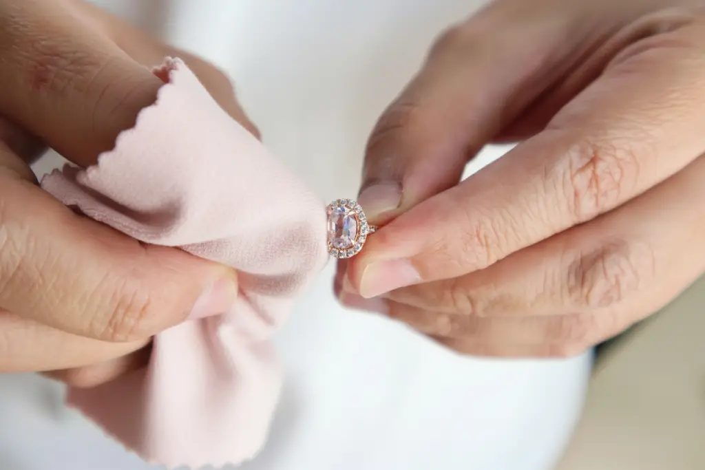 Ékszerész mikroszálas kendővel tisztít egy gyémántgyűrűt professzionális ékszerápolás során